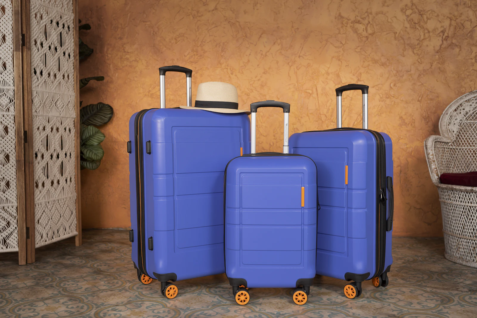 Three blue hard-shell suitcases in different sizes standing side by side